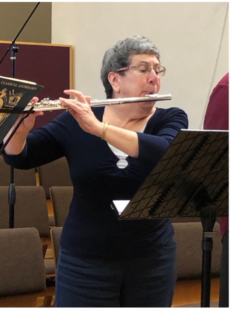 Grey-haired woman in a black sweater playing the flute