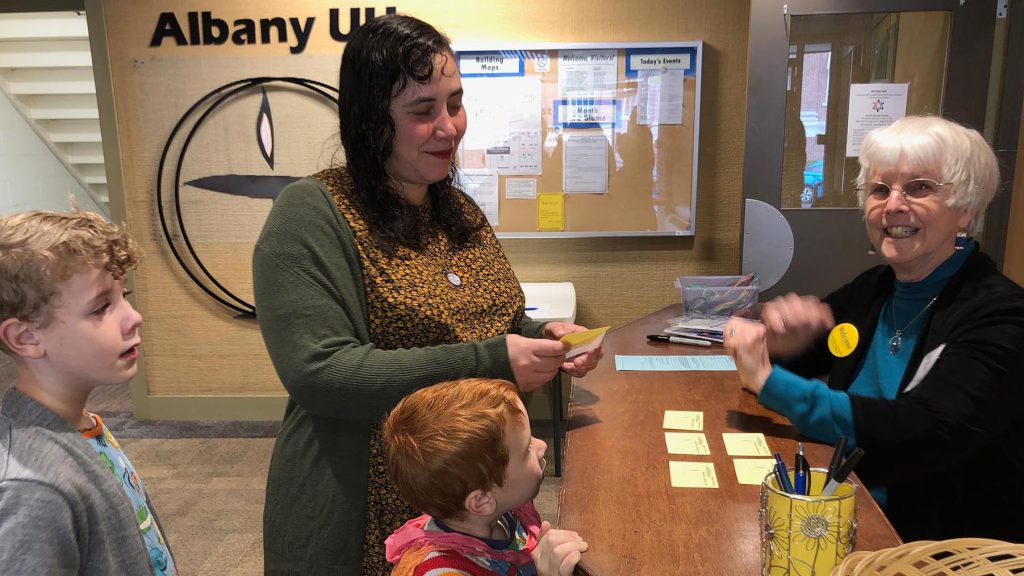 A smiling young mother and her two boys with a smiling white-haired woman at counter.