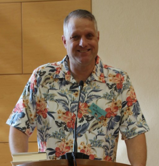 The sexton, a mid-age white man in colorful Hawaiian shirt smiling from the pulpit