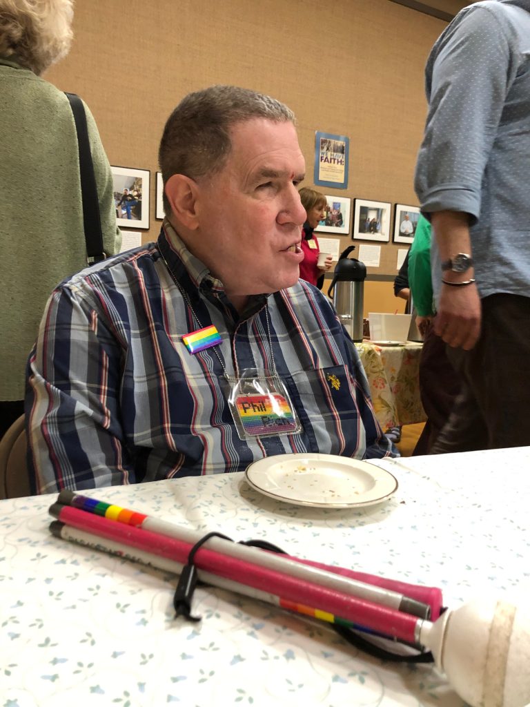 mid-life blind man in plaid shirt in conversation at a table in church hall coffee hour
