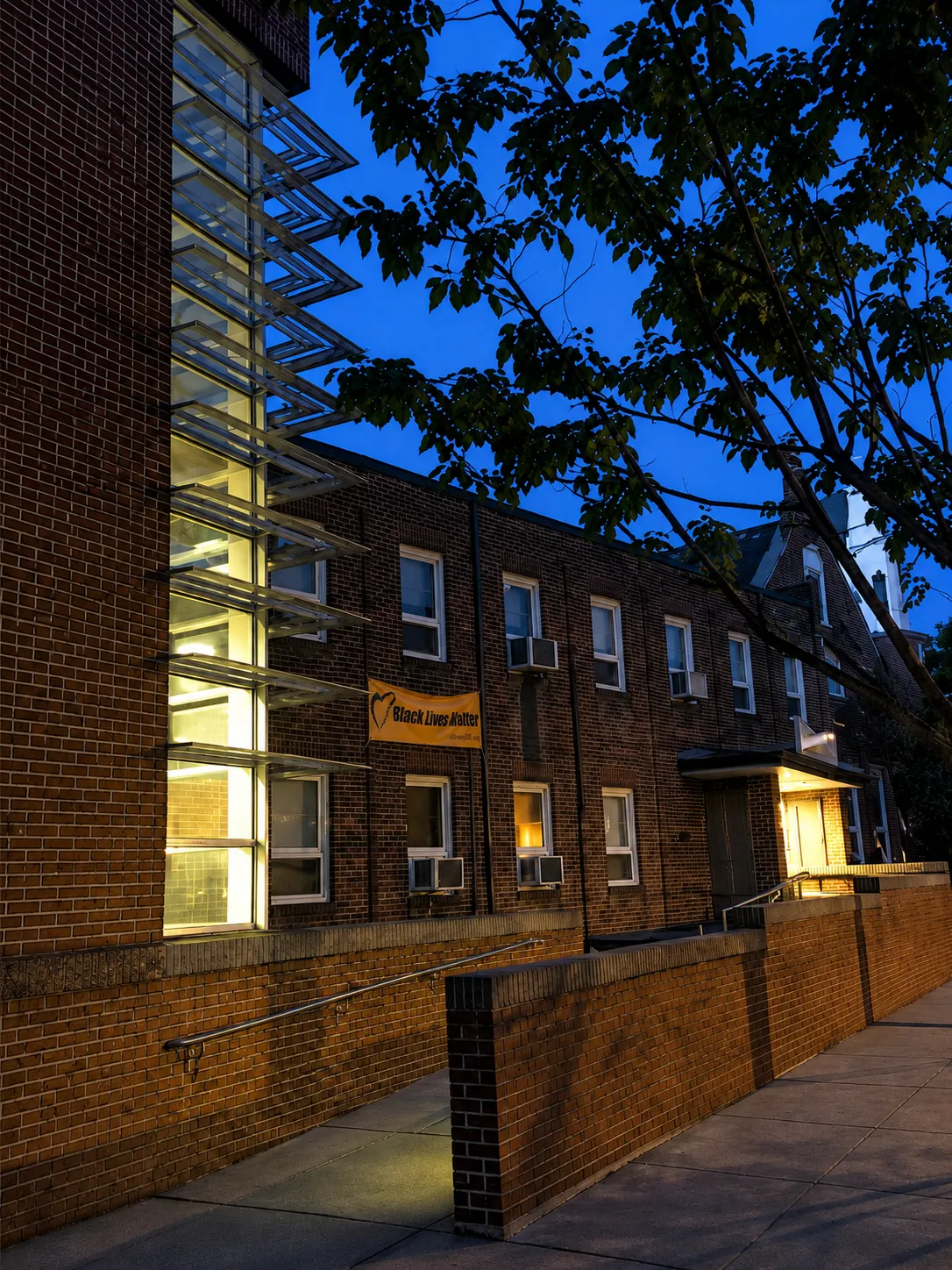 The church building lit up at dusk with a Black Lives Matter banner on the facade