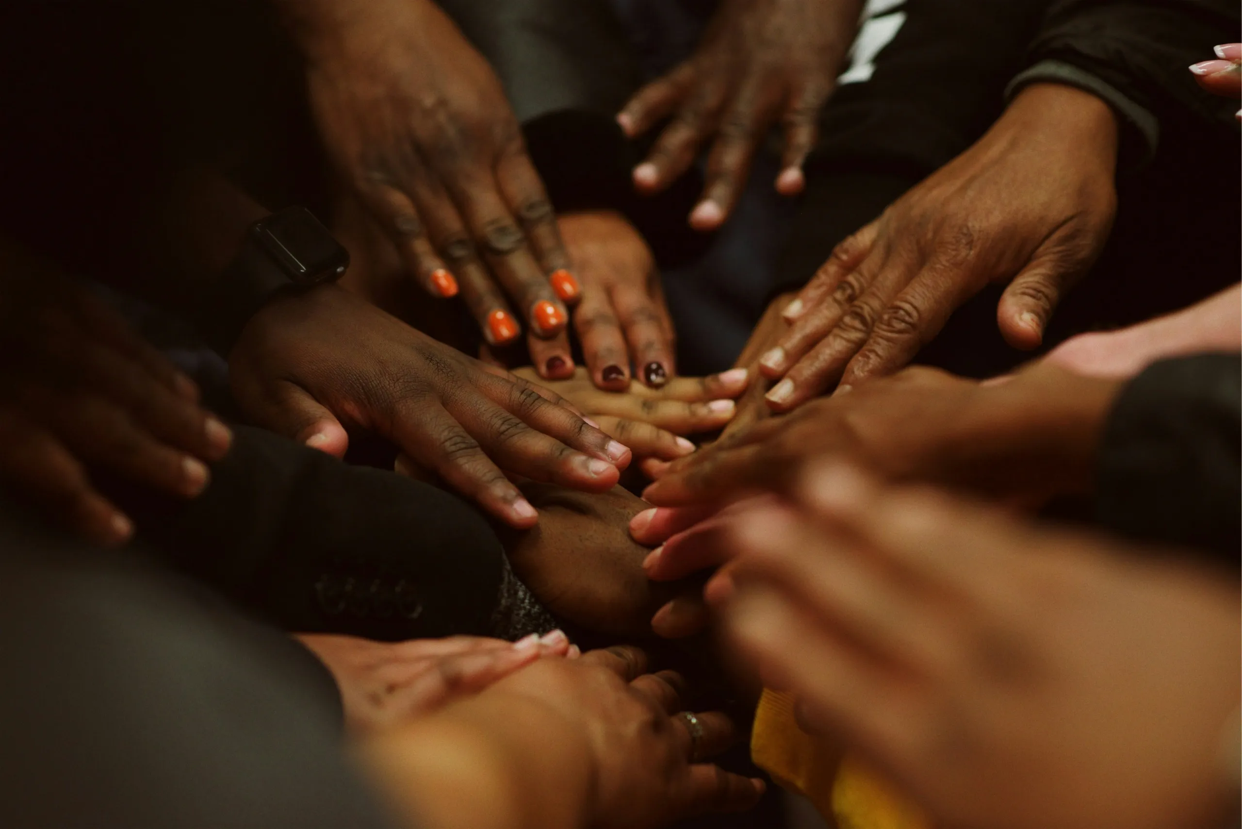 A close-up of many hands of different skin tones joined together in a circle
