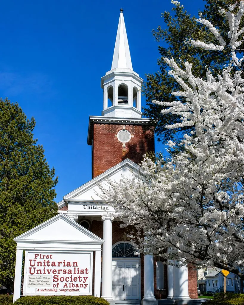 The First Unitarian Universalist Society of Albany church building in spring with a blossoming tree