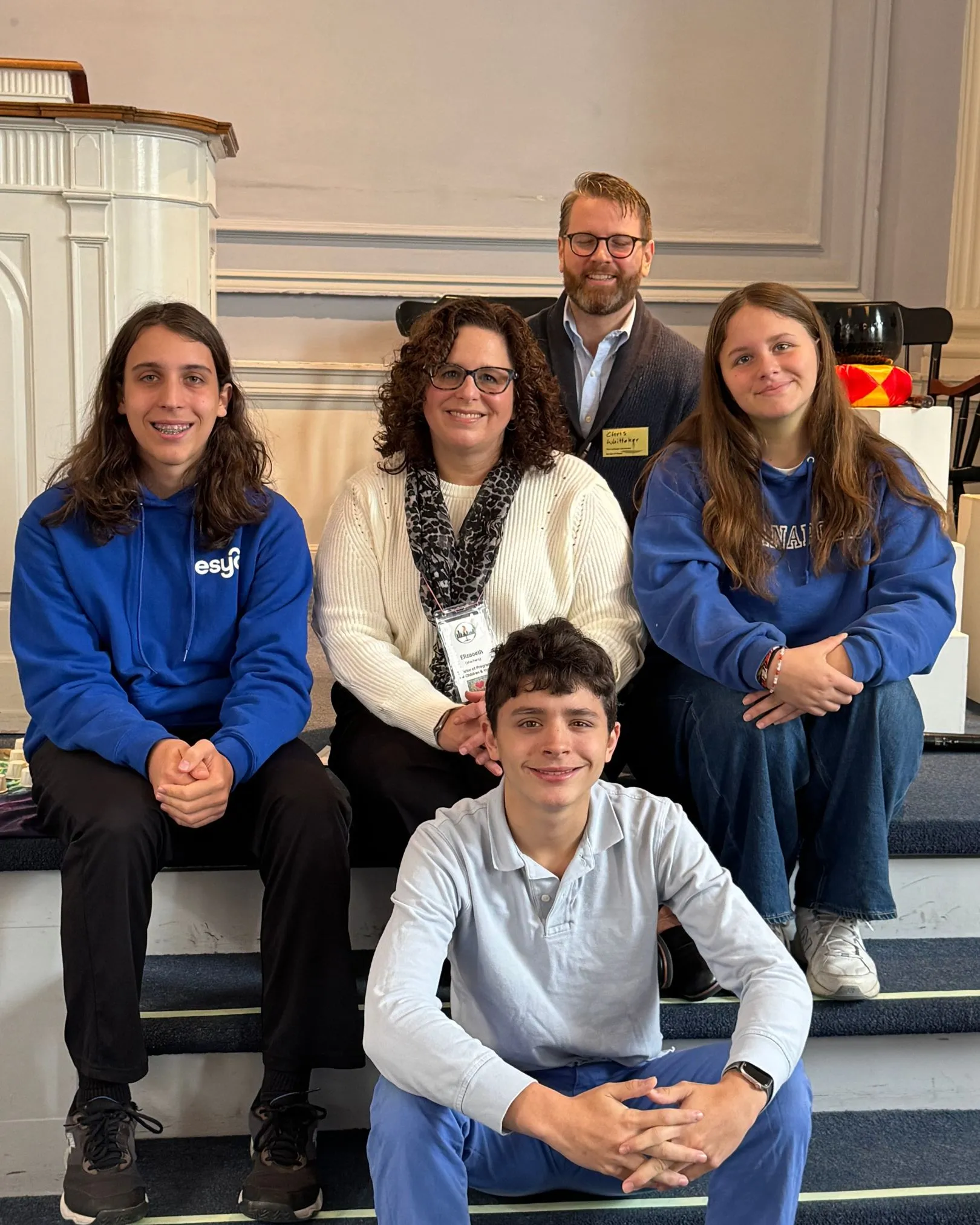 A group of five people, including teens and adults, posing together on sanctuary steps