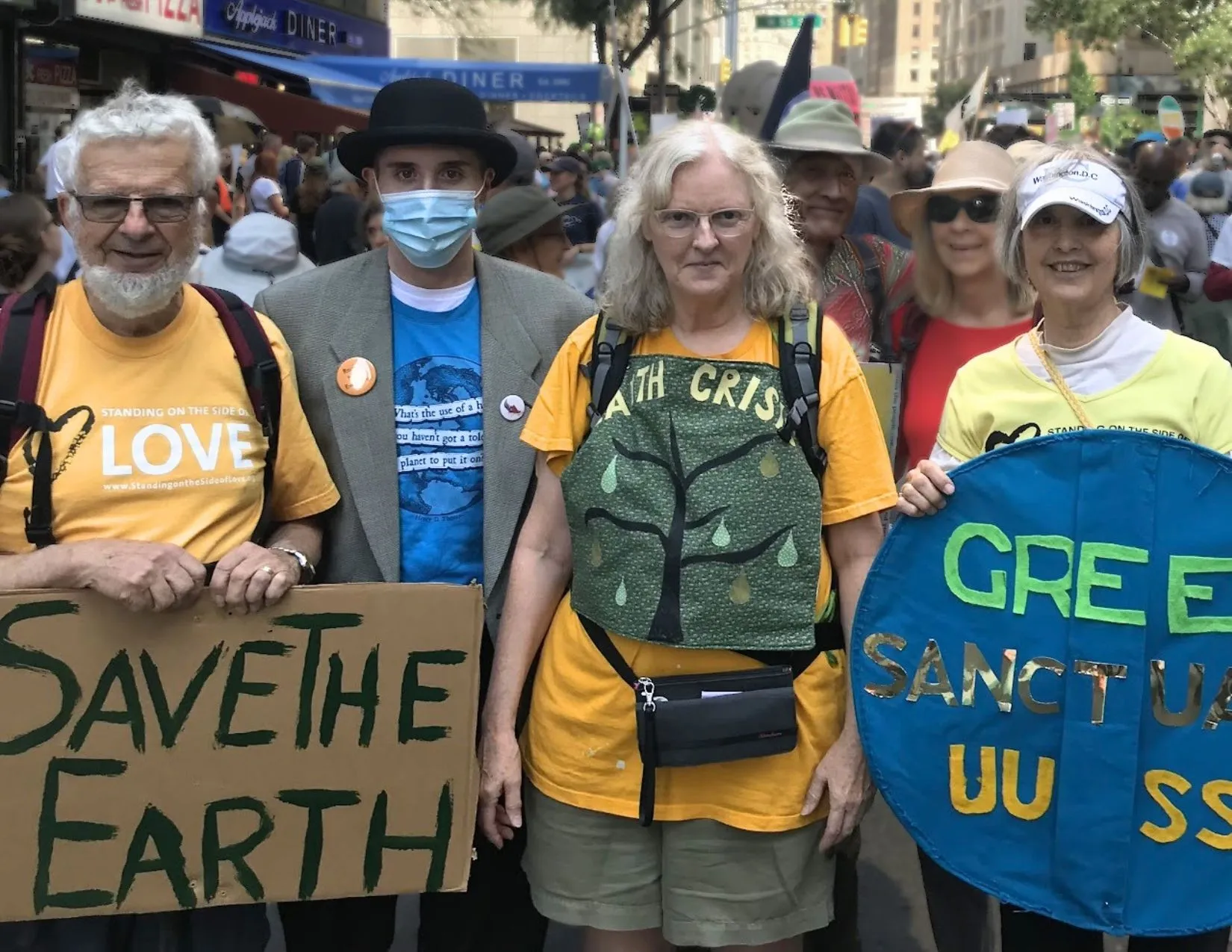 A group holding 'Save the Earth' and 'Green Sanctuary UU' signs at a march to end fossil fuels