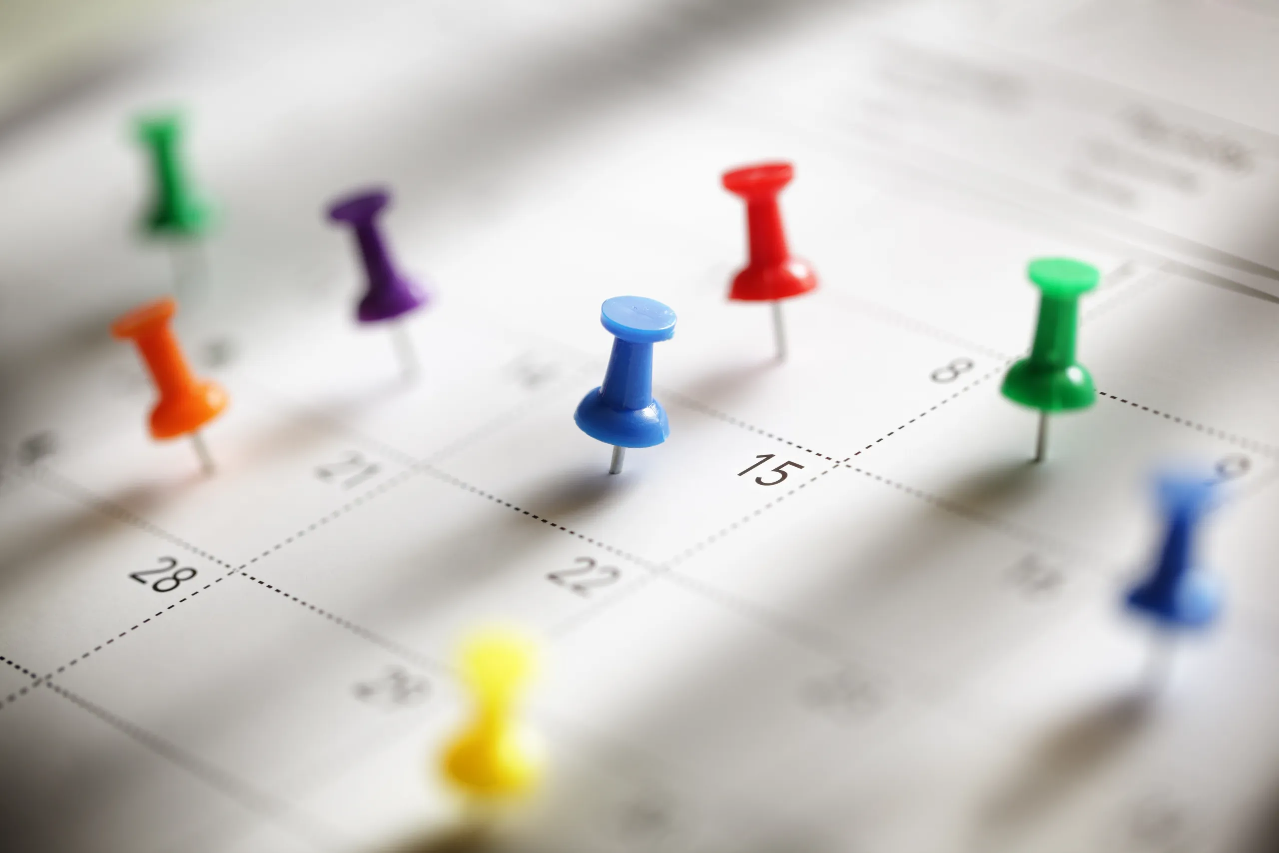 Colorful pushpins marking dates on a calendar