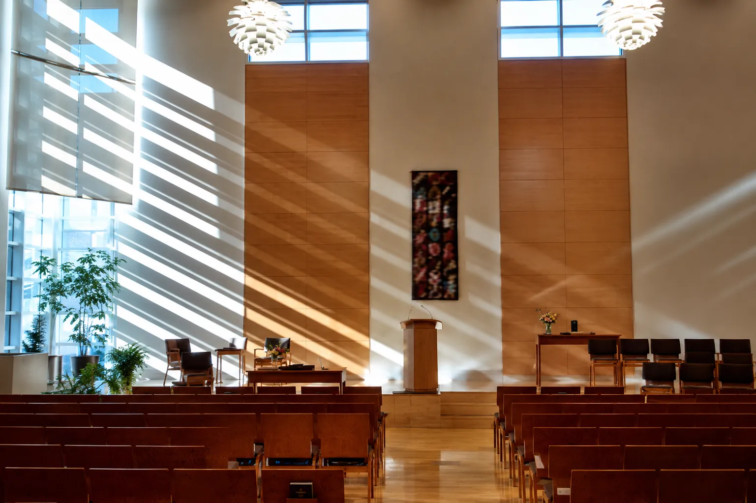 The sanctuary with pews, a podium, and stained light streaming through tall windows