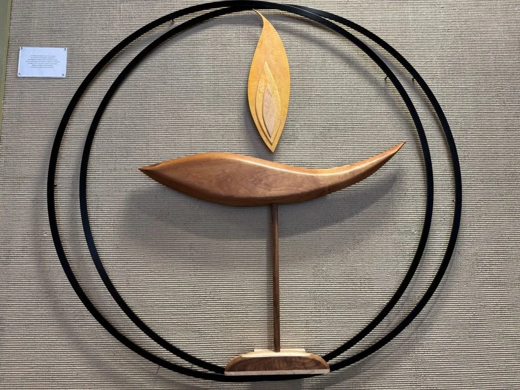 A wooden flaming chalice sculpture mounted in a ring stand