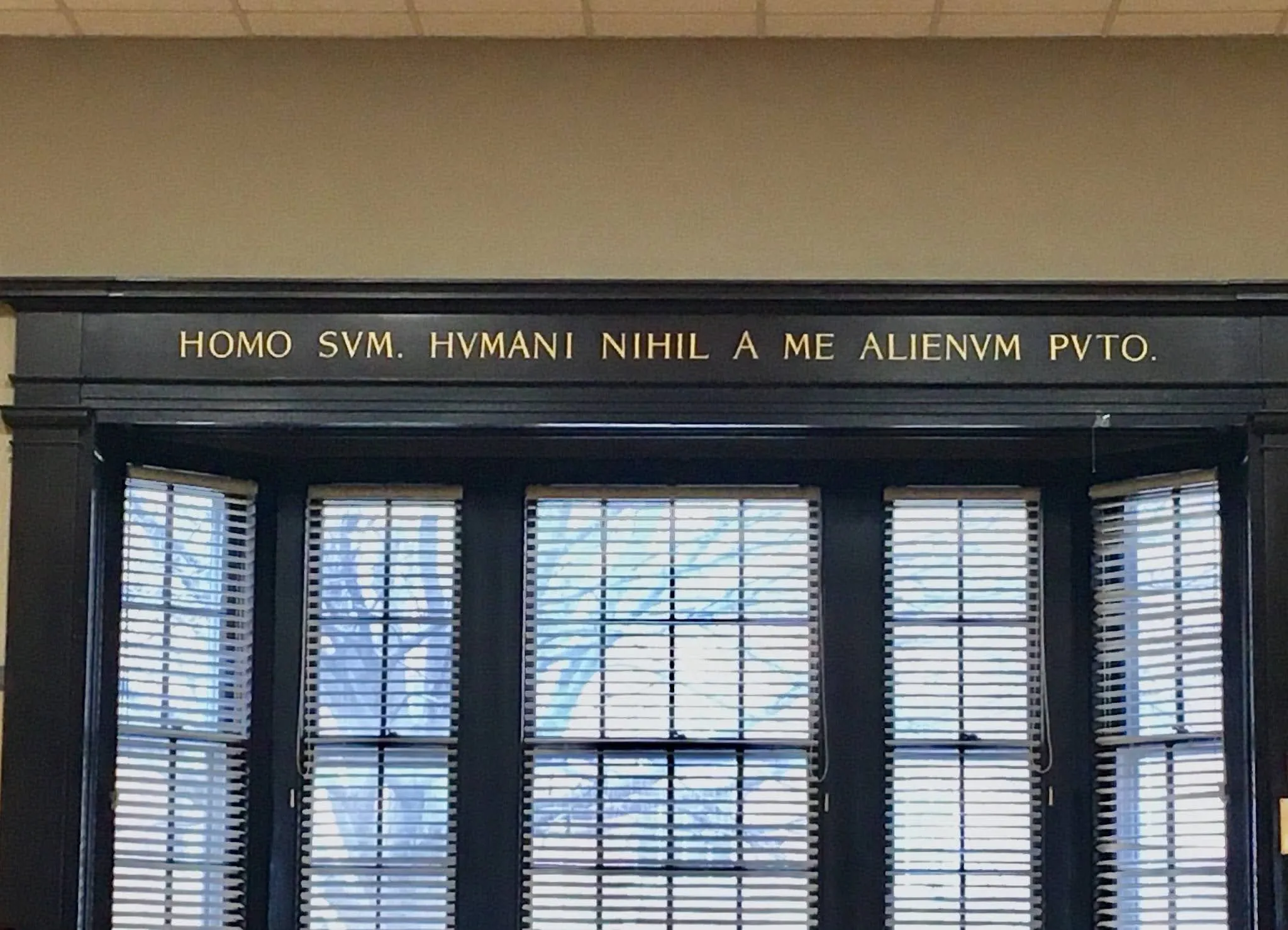 An engraved Latin plaque reading 'Homo sum, humani nihil a me alienum puto' mounted above a window