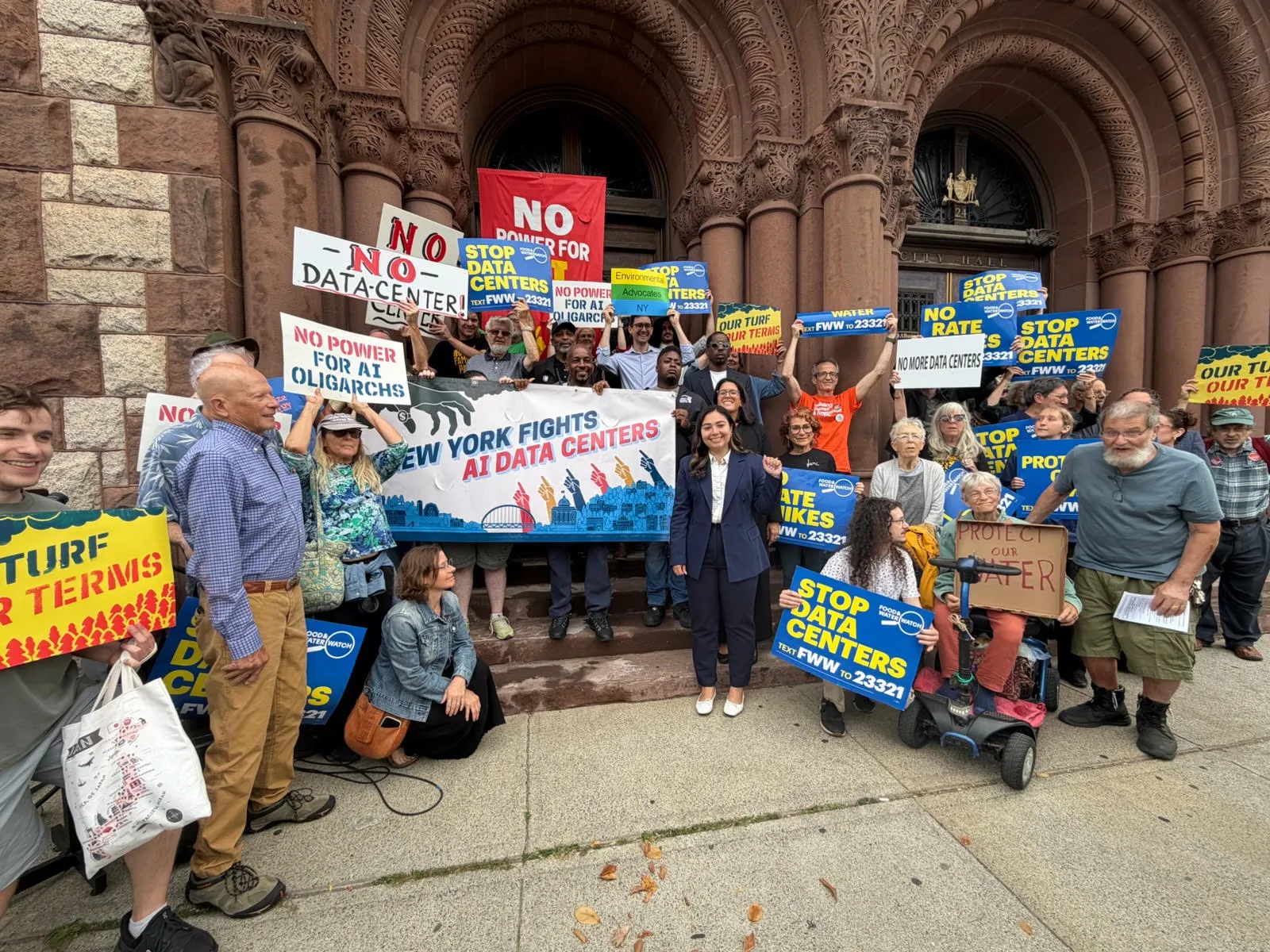 Advocates posing together at a rally with wind turbine props outside a state building