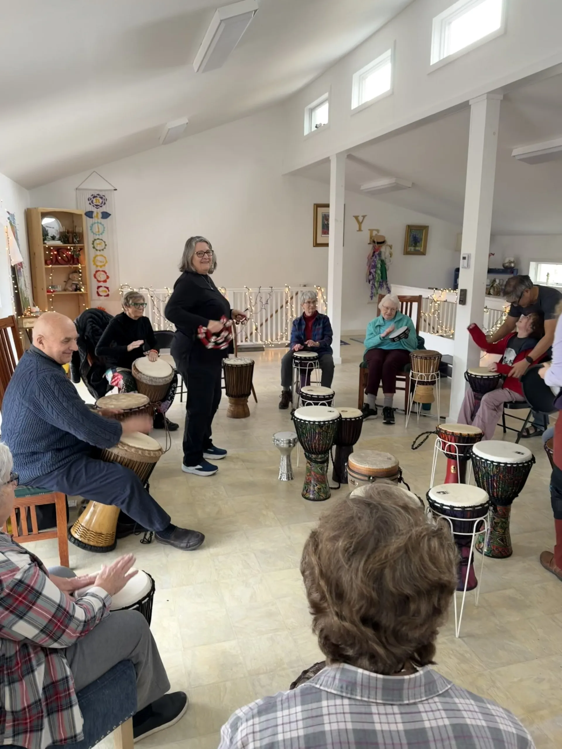 Adults and a child playing djembe drums in a circle during a community drum circle