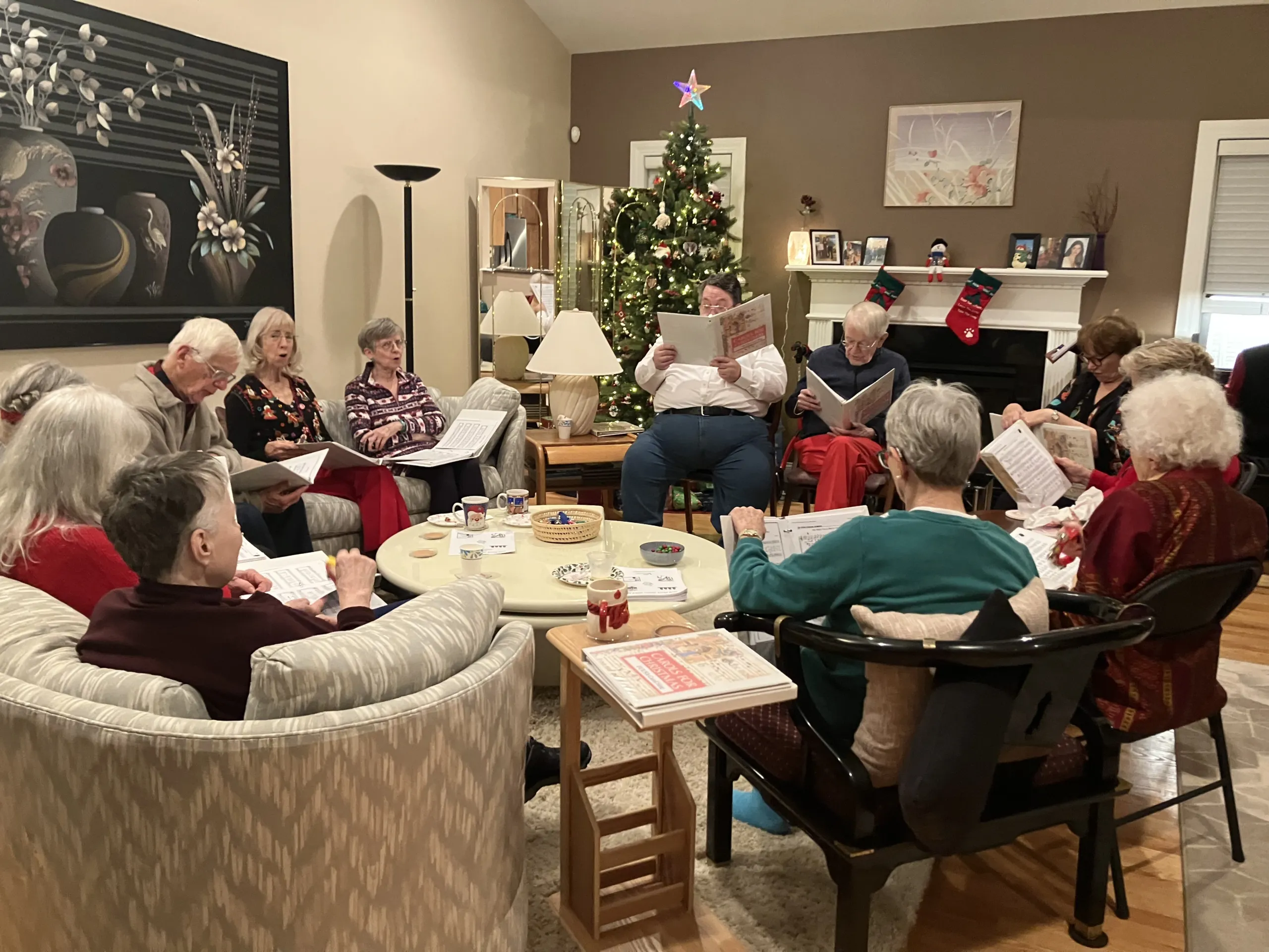 People holding songbooks and singing together by a Christmas tree at a holiday sing-along