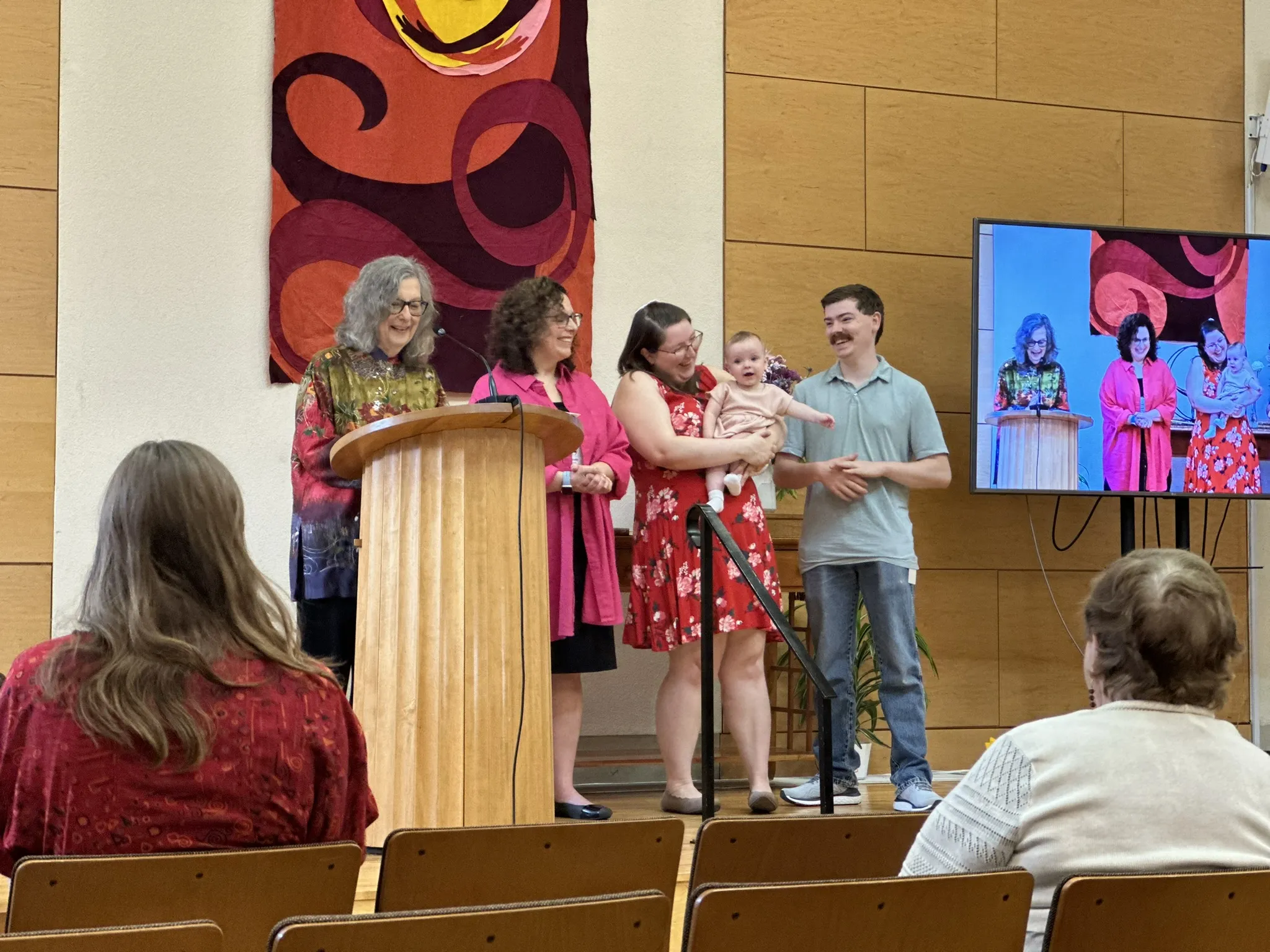A family holding a baby standing with two officiants during a child dedication ceremony