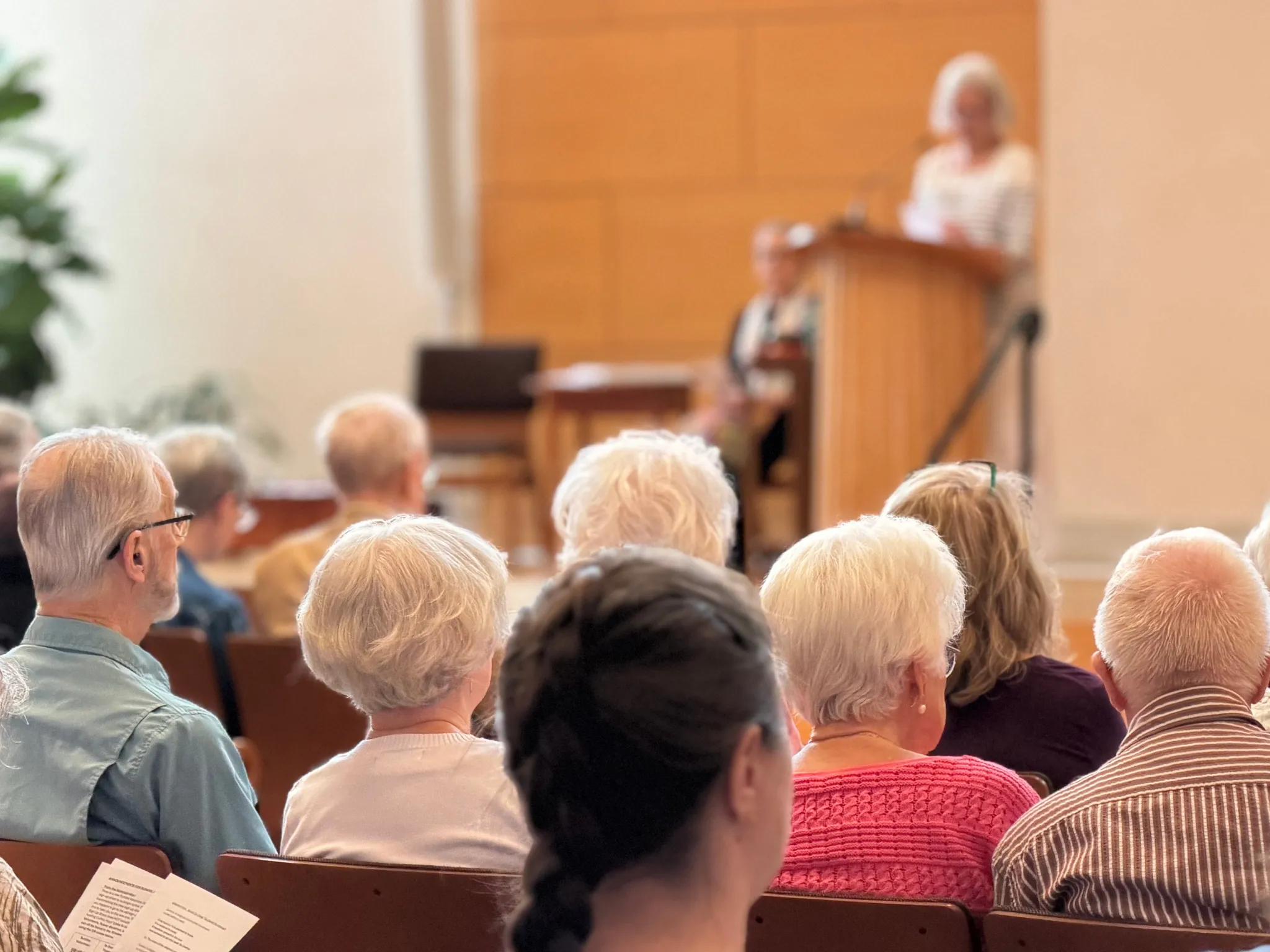Congregation members seated in pews listening to a speaker at a podium
