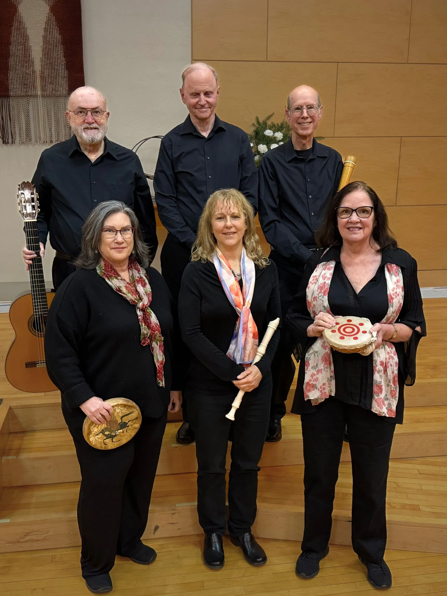 Six members of the Helderberg Madrigal Singers dressed in black, holding a guitar, recorder, and hand drums