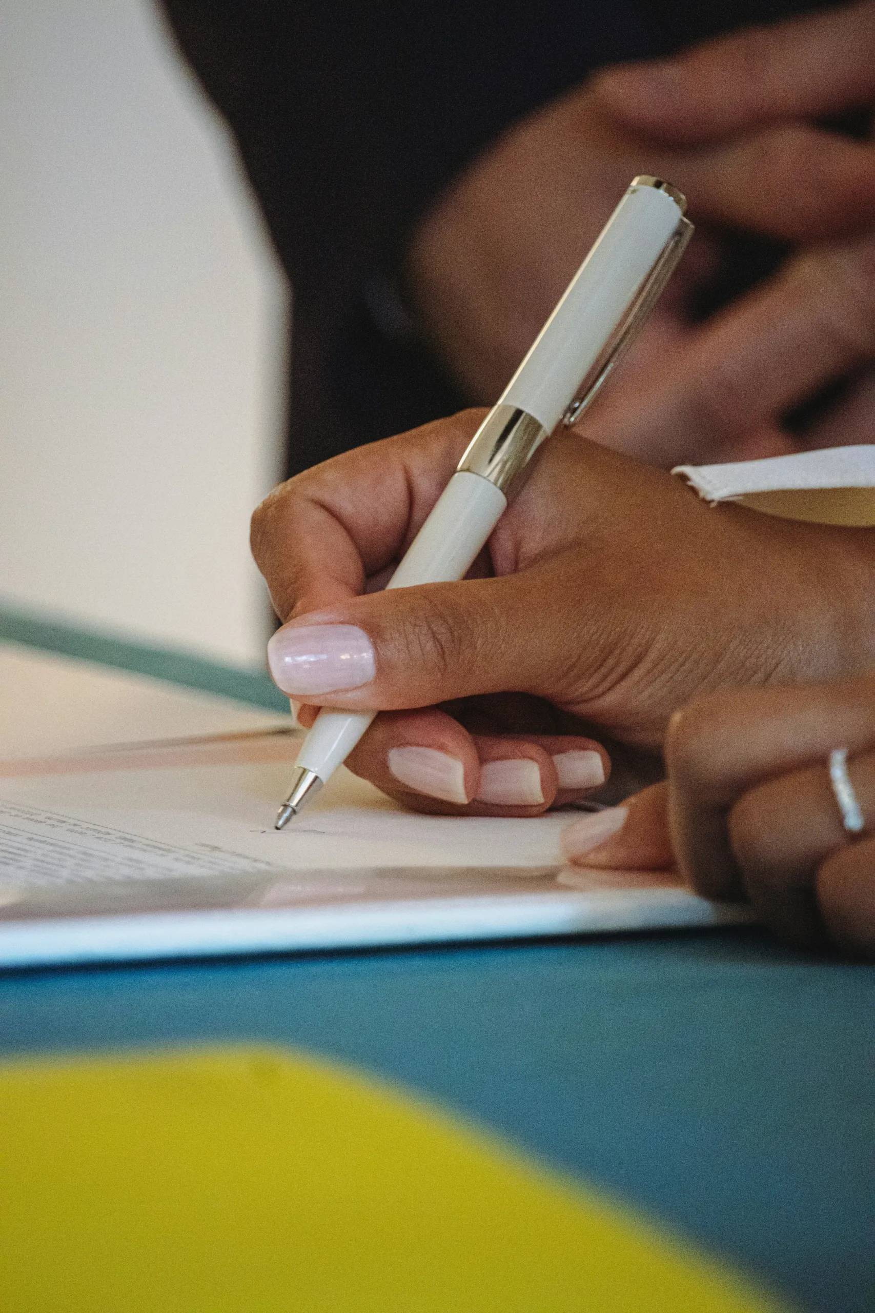 A hand writing a note with a white pen on a card